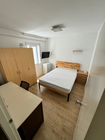 Habitación H13 · vista general con cama doble, armario, escritorio y televisión