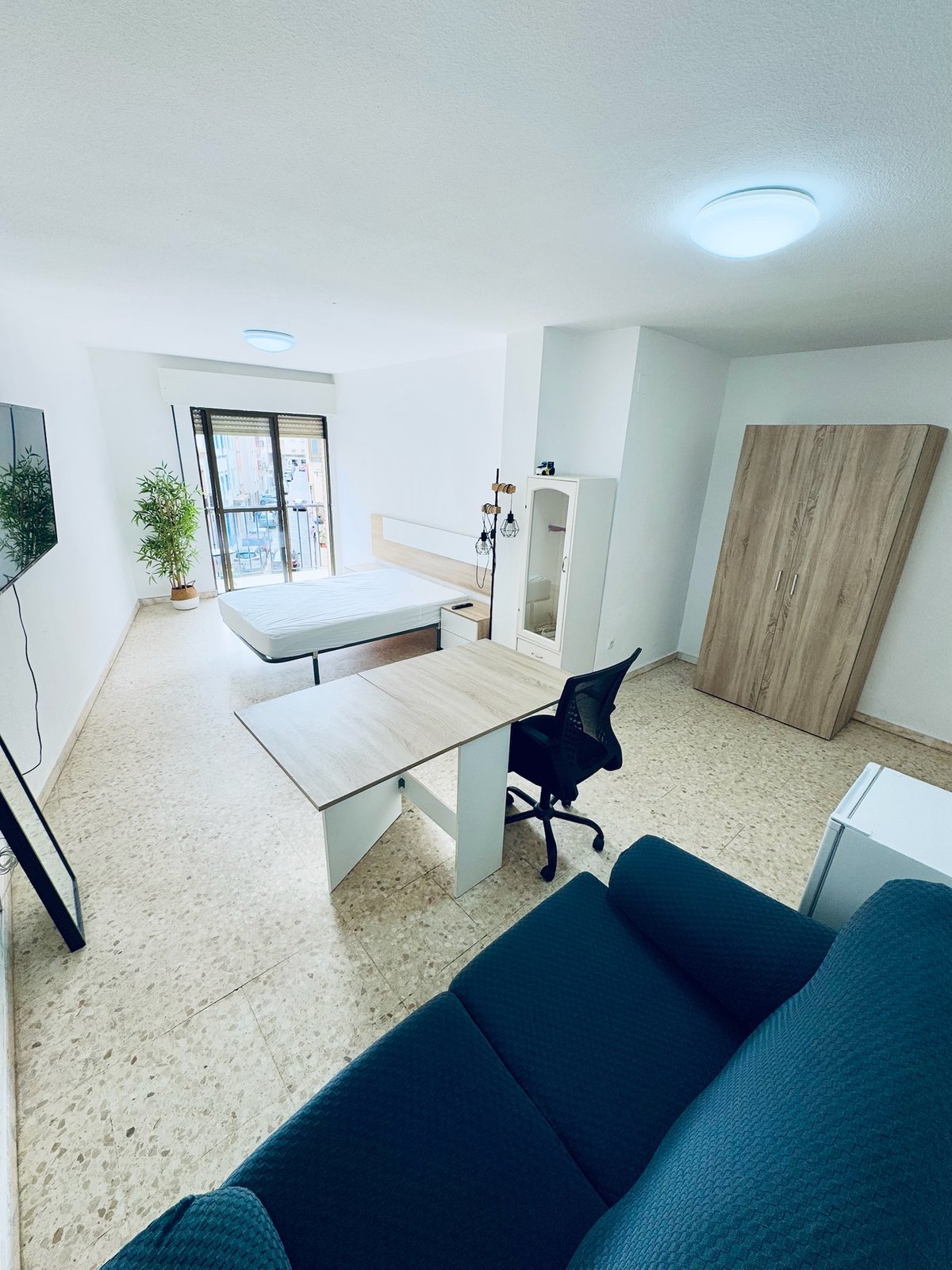 Habitación H42 · vista general con cama, mesa de trabajo, armario, sofá y mini nevera